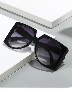 Close-up of oversized square sunglasses with black frames and purple gradient lenses
