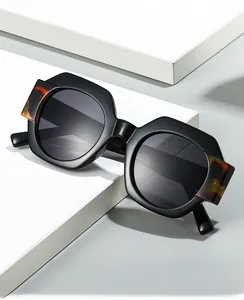 Macro detail of wide black frame sunglasses with tortoise pattern hinges on white blocks