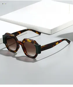 Detail of octagonal tortoiseshell sunglasses with green accents and gradient brown lenses