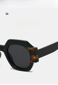 Detailed close-up of geometric sunglasses frame with tortoise pattern and metal hinges