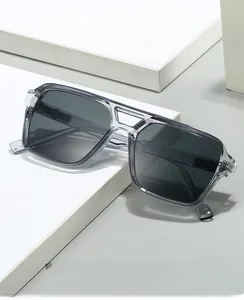Détail de lunettes de soleil carrées à double pont gris clair sur des supports blancs