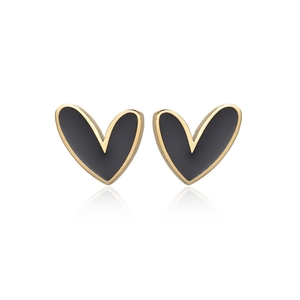 Macro shot of gold-plated heart stud earrings with matte black enamel inlay on white background