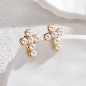 Detailed macro view of cross earrings featuring gold plating and white pearl inlays