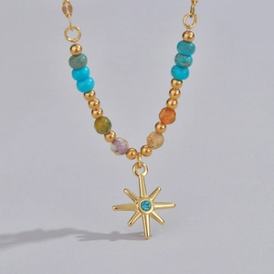 Detail of beaded necklace with golden starburst pendant and vibrant colorful stones