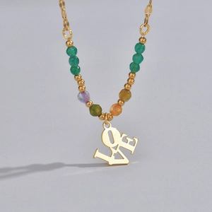 Detail of a gold necklace featuring a LOVE pendant and colorful natural stone beads