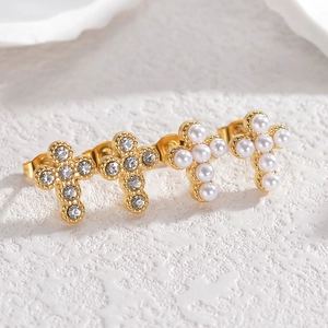 French style gold cross earrings set with pearls and rhinestones on stone background