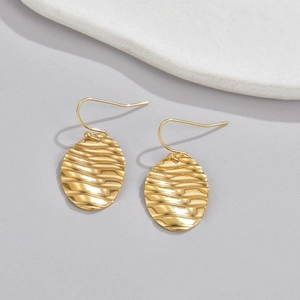 Close-up of golden drop earrings with 18k gold plating and water ripple texture