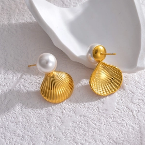 Minimalist stainless steel shell stud earrings with white pearl on a ceramic pedestal