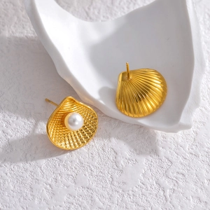Detailed view of gold scallop shell earrings with white pearl inlay and ribbed texture