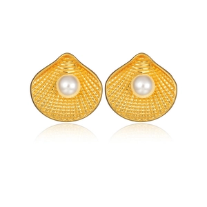 Macro detail of gold scallop shell earrings featuring white pearl and fine ribbed texture