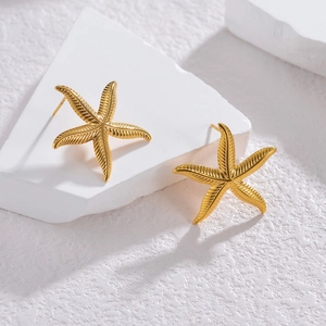 Golden starfish stud earrings in stainless steel on white stone display props