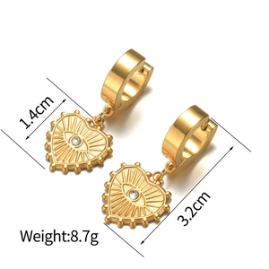 Boucles d'oreilles créoles cœur dorées avec œil protecteur et cristal sur fond blanc