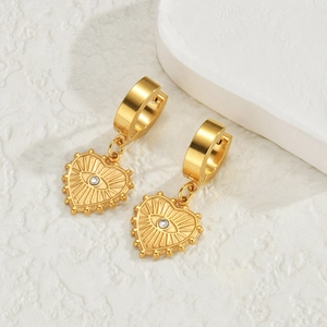 Boucles d'oreilles cœur dorées avec motif œil et cristal sur présentoir blanc