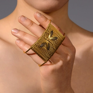 Détail d'un bracelet de paume doré avec bande tissée et libellule en relief 3D