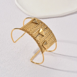 Bracelet manchette tressé en acier doré avec clous pyramides et détails en zircon
