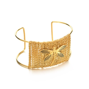 Détail d'un bracelet manchette libellé doré avec texture tissée ajourée et finition métallique