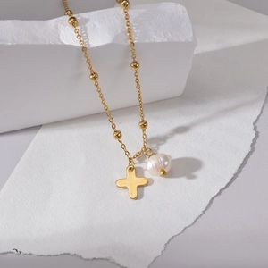 Détail du collier plaqué or 14K avec un pendentif croix et un accent de perle élégant