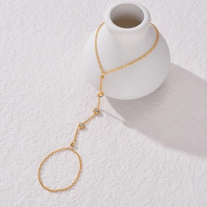 Bracelet bague chaîne dorée minimaliste avec trois strass ronds clairs sur fond blanc