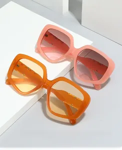 Detail view of large square gradient sunglasses with metal rivet hinges on white podium