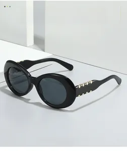 Détail de lunettes de soleil ovales noires avec décoration métallique dorée sur la branche