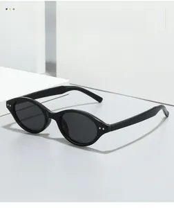 Close-up of black oval sunglasses with metallic rivet detail on white geometric stands