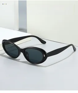 Detail of sleek black oval sunglasses with silver metal hinge accents on white background