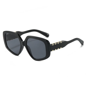Oversized black polygon sunglasses with thick frame and gold metal accents on the temples