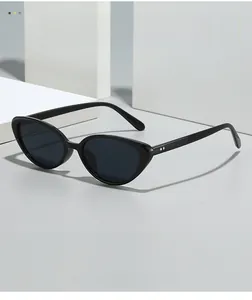Close-up of black cat-eye sunglasses with dark lenses on a white geometric block