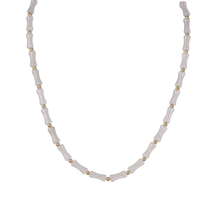 Detail of bone-shaped grey beads and gold spacers on a minimalist beaded necklace