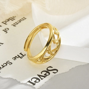 Detail of the golden hollow heart-shaped ring on a textured stone and paper base