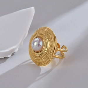 Bague vintage dorée avec textures spirales concentriques et perle centrale au style minimaliste