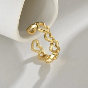 Minimalist gold hollow heart open ring displayed on white cylinder prop with soft shadows