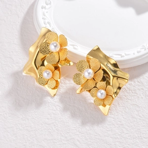 Close-up of golden metal flower earrings featuring matte petals and white pearls