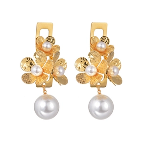 Detailed macro view of vintage gold flower earrings with white pearl and hammered metal