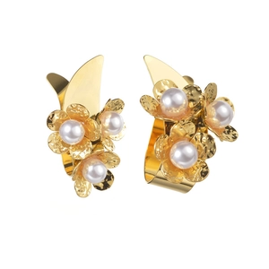 Detail of golden flower earrings featuring hammered texture and white pearls