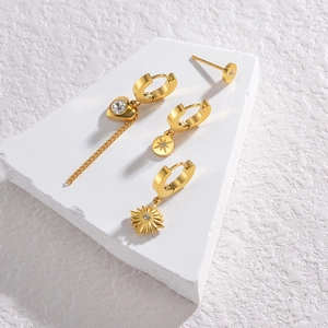 Goldfarbenes Edelstahl Ohrring Set mit Herzanhängern und Zirkon Quasten auf weißem Stein