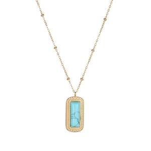 Close-up of gold square pendant with blue marble stone and vintage leaf relief detail