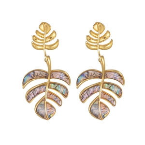 Macro view of gold leaf earrings with abalone shell inlays and textured metal details