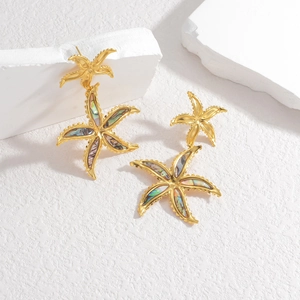 Golden starfish stud earrings featuring colorful abalone shell inlays on white stone display