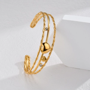 Elegant gold hollow heart open cuff bracelet with zircon accents on a marble base