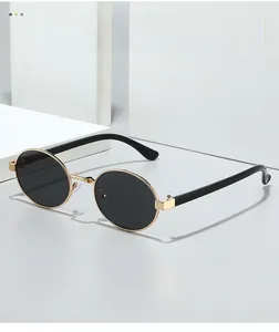 Detail view of oval cat-eye sunglasses with gold metal frame and black lenses