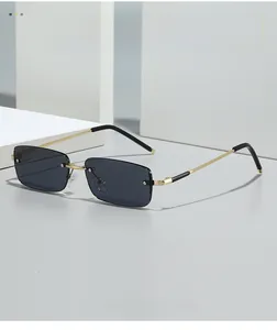 Close-up of rimless rectangle sunglasses with dark grey lenses and gold metal frame