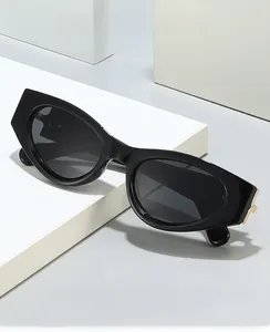 Detail of black oval sunglasses with golden metal temple accent on a minimalist pedestal