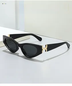 Close-up of black cat-eye sunglasses with elegant gold metal hinge detail and gray lenses