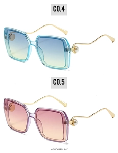 Detail einer quadratischen Oversize-Sonnenbrille mit goldfarbenen Wellenbügeln und Perlen