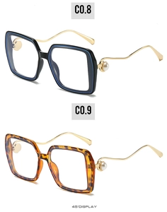Detailansicht der quadratischen Brille mit goldenen Wellenbügeln und Perlenbesatz