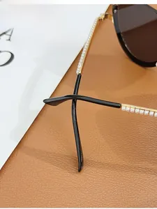 Close-up of golden metal sunglasses temples with pearl inlay and curved black tips