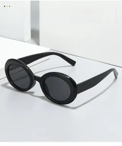 Close-up of black retro oval sunglasses on white geometric blocks showing texture material