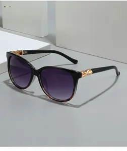 Detail of cat-eye sunglasses with golden twist metal hinge and purple gradient lenses