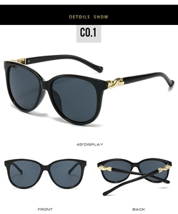 Close-up of stylish black oversized sunglasses with elegant gold twist metal hinge detail